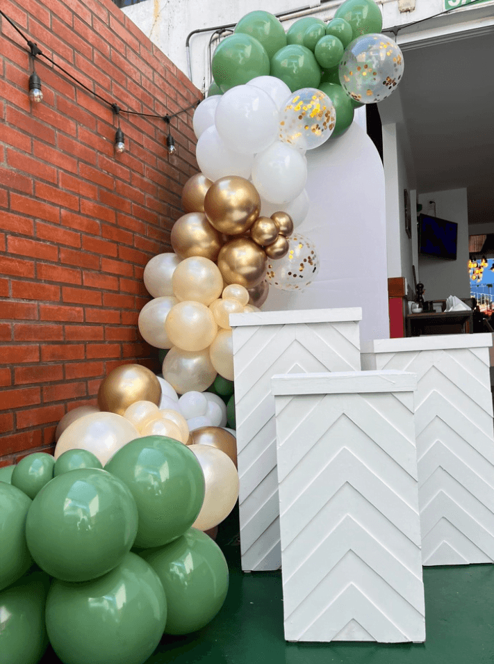 Arco de globos verdes, blancos y dorados con pedestales