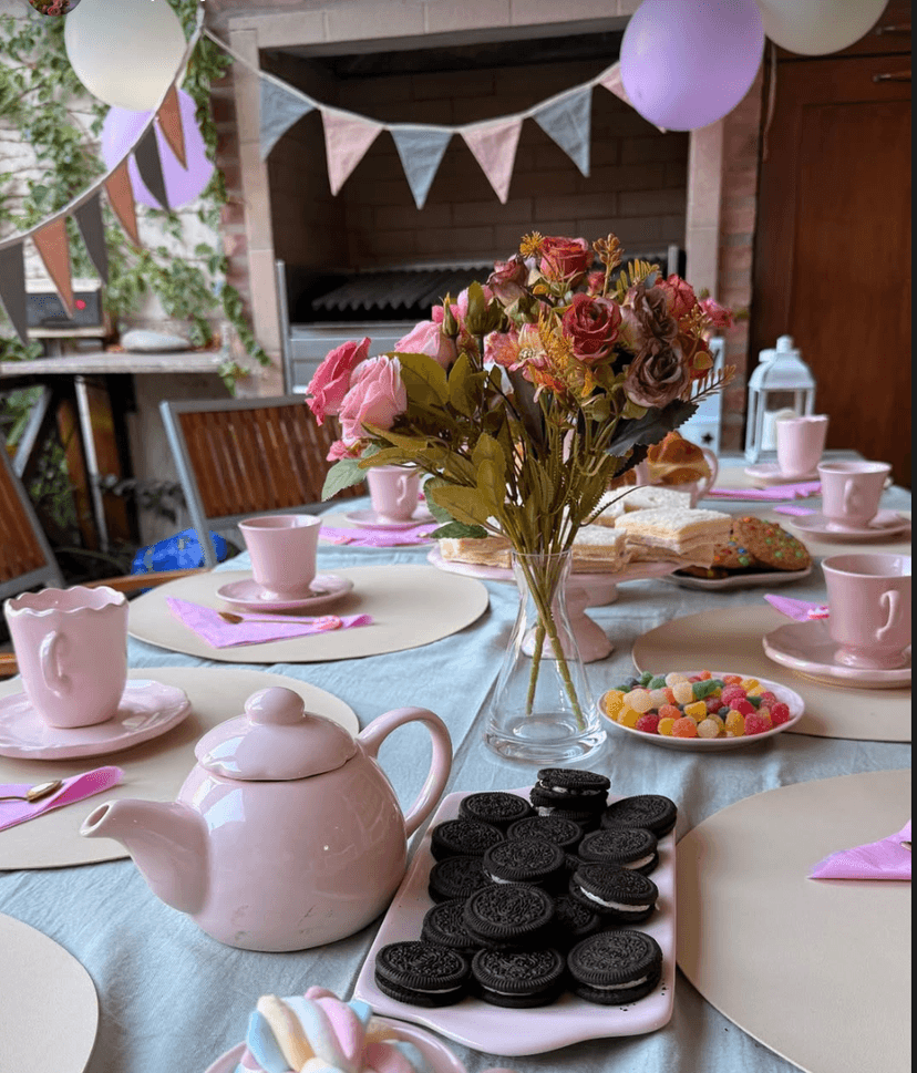 Mesa de tea party con teteras, tazas rosas y flores